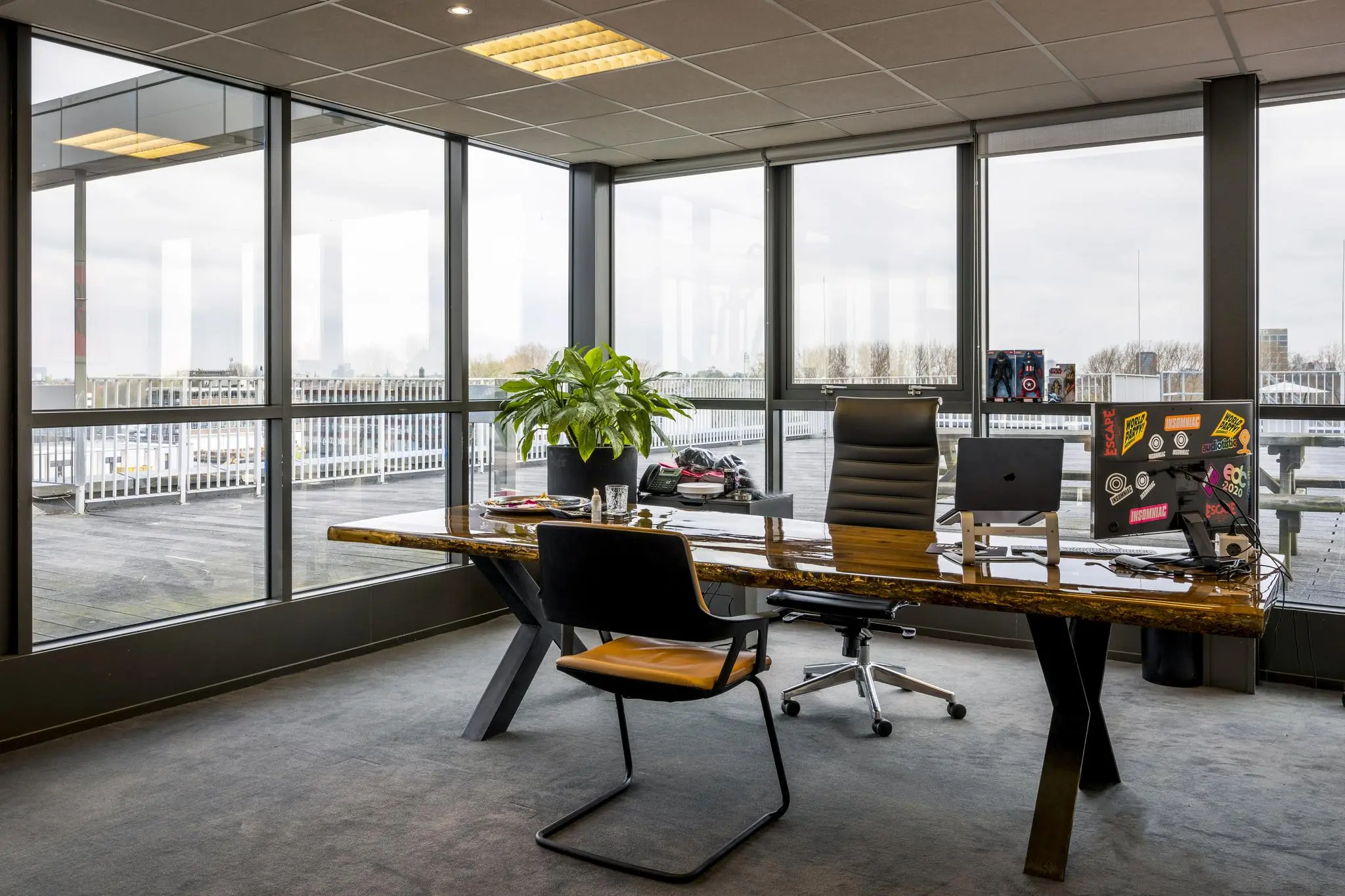 Modern kantoor aan de Anthony Fokkerweg met een houten bureau, grote ramen en uitzicht op een dakterras.